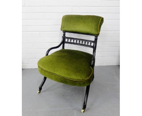 An ebonised side chair with an upholstered back and seat on shaped supports terminating in ceramic castors 