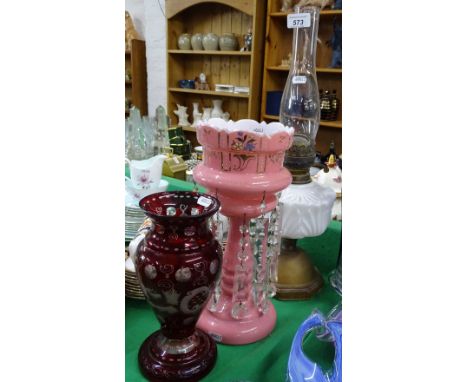 An Edwardian pink milk glass table lustre with drops, and an oil lamp and a ruby overlay vase.