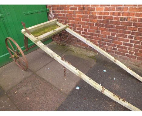 A VINTAGE WOODEN FRAMED TWO CAST WHEELED AGRICULTURAL IMPLEMENT