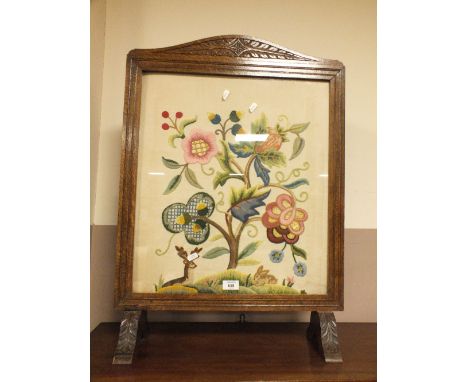 A CARVED OAK GLAZED FIRESCREEN WITH NEEDLEWORK DETAIL