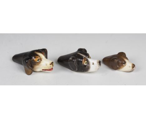 Three Royal Worcester porcelain whistles, 1920s, each modelled as a dog's head, puce printed marks to bases, length of longes