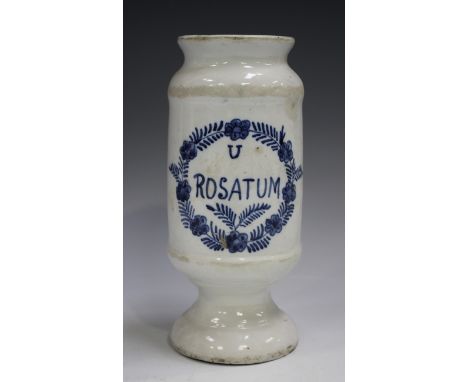 A tin glazed cylindrical dry drug jar, 19th century, inscribed in blue 'U Rosatum' within a foliate cartouche, raised on a ci