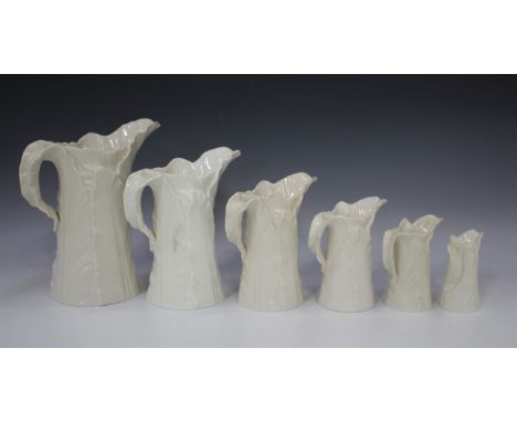 A set of six Royal Worcester white glazed graduated leaf moulded jugs, various dates, and a matching two-handled sugar bowl, 