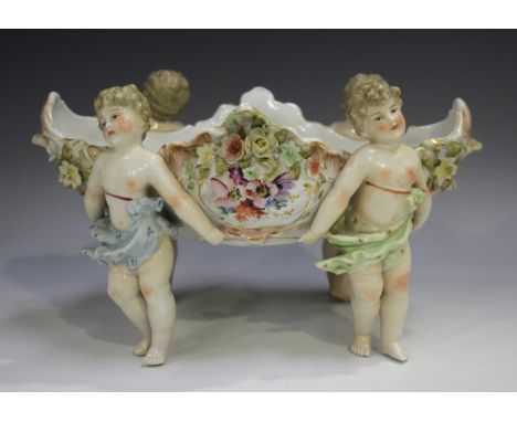 A Sitzendorf centrepiece, late 19th/early 20th century, modelled as four putti supporting a floral encrusted oval basket, hei