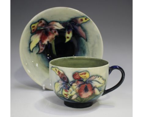 A Moorcroft Orchid pattern teacup and saucer, 1928-49, impressed and painted marks to bases, saucer diameter 14cm.Buyer’s Pre