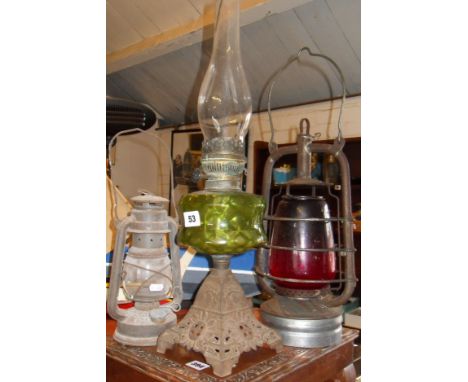Victorian oil lamp with green glass reservoir on iron base, and two Hurricane lamps