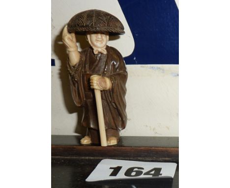A signed Japanese hardwood netsuke of an old man with hat & cane