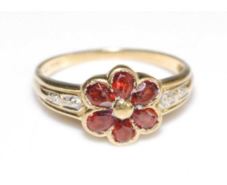 An 18ct yellow gold garnet flower shaped cluster ring, with six pear shaped garnets in bezel settings, with two 0.85mm single