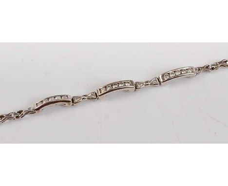 A white metal diamond line bracelet, featuring three curved bars each channel set with five round brilliant cut diamonds inte