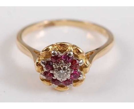 A yellow and white metal, ruby and diamond reverse circular cluster ring, with centre round brilliant cut diamond within a bo