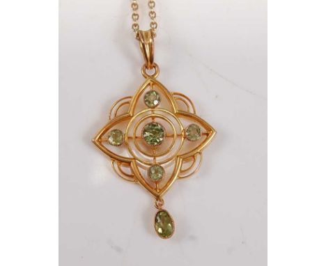 A yellow metal peridot quatrefoil pendant, comprising four round faceted peridots in an openwork surround, with an oval perid