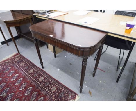 AN ANTIQUE MAHOGANY FOLD OVER CARD TABLE ON TURNED TAPERING SUPPORTS 