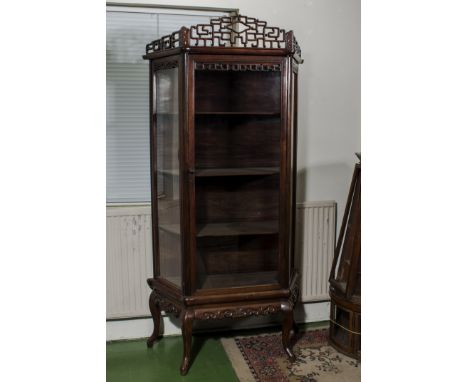 A Chinese hard wood display cabinet, early 20th century, with pierced surmount above a glazed cupboard door, on a scroll carv