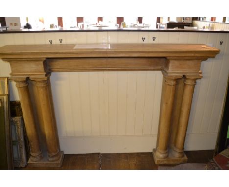 A late 19th / early 20th century stripped pine fire surround, having a moulded cornice above four column supports, on a plint