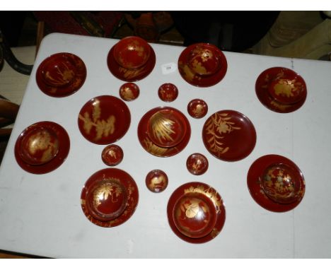 A Japanese red and black lacquered part saki/ tea service, parcel gilded in hiromaki with flowers and trees.