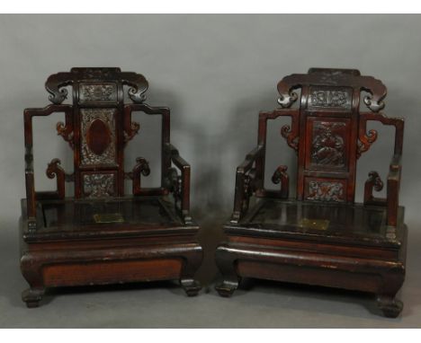 A near pair of Chinese carved pine low seated elbow collection chairs, having foliate carved and pierced cresting rails above