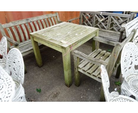 A 20th century hardwood square garden table, a matching open armchair and a bench, 140cm wide x 90cm high (3).