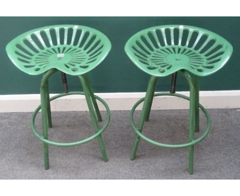 20th century design; a pair of green painted metal stools with tractor style seats, each 50cm wide x 68cm high, (2).