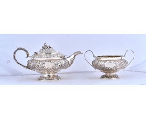 A George IV silver teapot, of compressed circular form, with floral and foliate embossed and engraved decoration, the hinged 