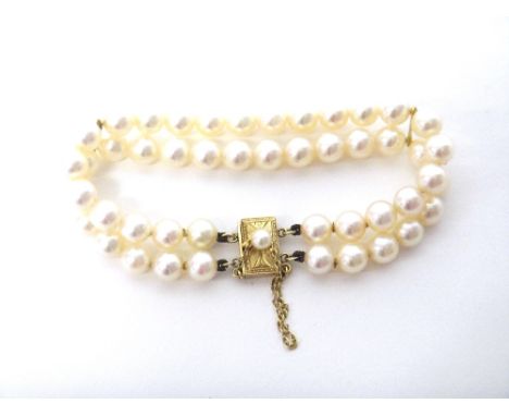 A two row bracelet of uniform cultured pearls, on a rectangular gold clasp, mounted with a cultured pearl, detailed K 14, fit