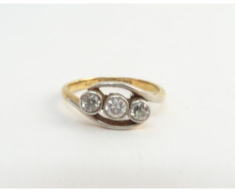 A gold and platinum, diamond set three stone ring, mounted with a row of cushion shaped diamonds, in a crossover design, deta