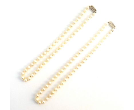 Two single row necklaces of uniform cultured pearls, each on a gold and diamond set clasp, in a cut cornered rectangular desi