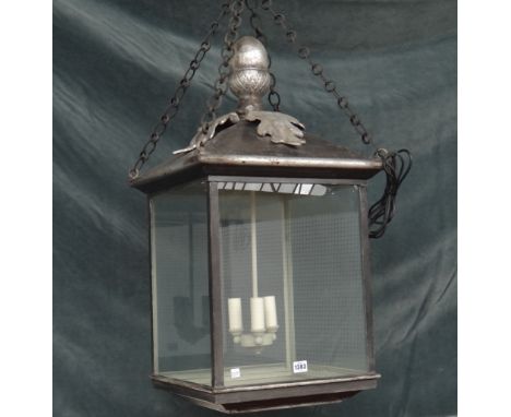 A modern silvered metal hall lantern of square form with an acorn finial, pitch roof and internal three light fitment. 80cm h