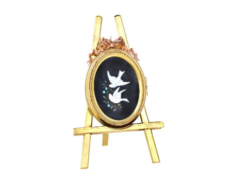 A brass pietra dura folding photograph frame, circa 1900, depicting two doves in flight, in an oval hinged frame, mounted on 