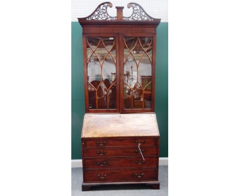 A George III mahogany bureau bookcase, the pierced scrolling swan neck pediment above a pair of astragal glazed doors, with f