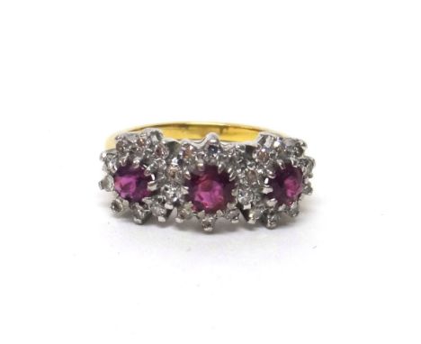 A gold, ruby and diamond set ring, in a triple cluster design, claw set with three circular cut rubies, surrounded by circula