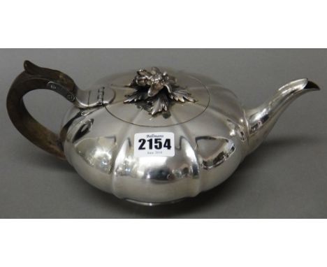 A George IV silver teapot, of compressed melon shaped form, the hinged lid with a cast floral and foliate finial, raised on a