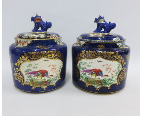 Pair of Booths Worcester style pottery jars,  painted with peacocks against a blue scale ground, the covers with temple dogs,