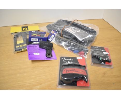 A bundle of accessories including guitar maintenance kit, Fender capo and grip aid, hercules cradle, tuner etc