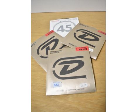 Four sets of bass guitar strings (3 x Dunlop, 1 x Fender)