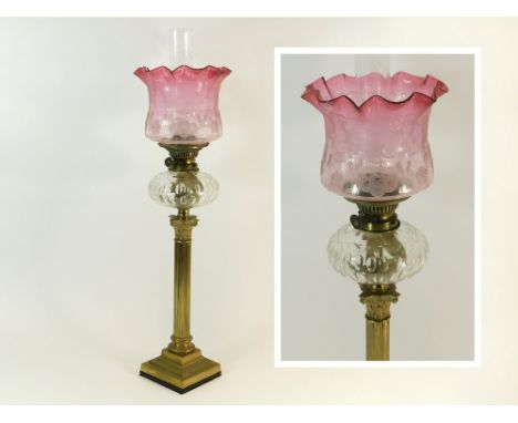 OIL LAMP. A Victorian oil lamp with cut, clear glass fount, brass Corinthian column & etched cranberry glass shade. Height 77