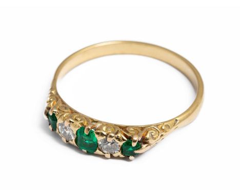 An 18ct yellow gold emerald and diamond five-stone ring, having three emerald cut emeralds and two old cut diamonds, scrollin
