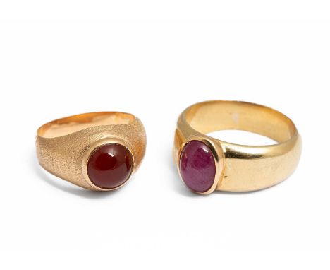 Two yellow metal and gem set rings, one set with a cabochon ruby, the other with a carnelian, ring size U and P½, unmarked as