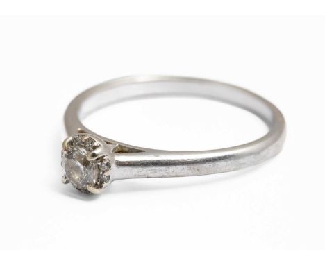 A diamond solitaire ring, the claw set round brilliant cut diamond approximately 0.25ct, within a halo of smaller round cut d