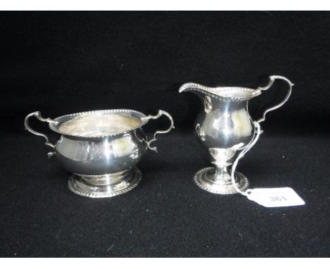 A CHESTER SILVER TWO HANDLED SUCRIER on foot with bead decoration and a matching milk jug ensuite