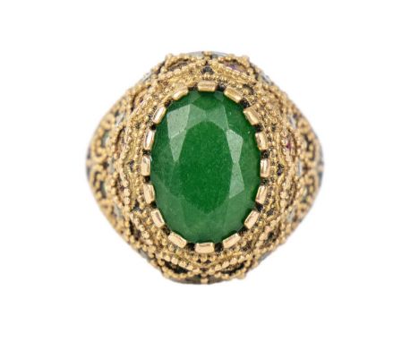 An Indian silver and gold plated ring. With a large oval cut emerald, the shoulders set with small rubies, emerald and white 