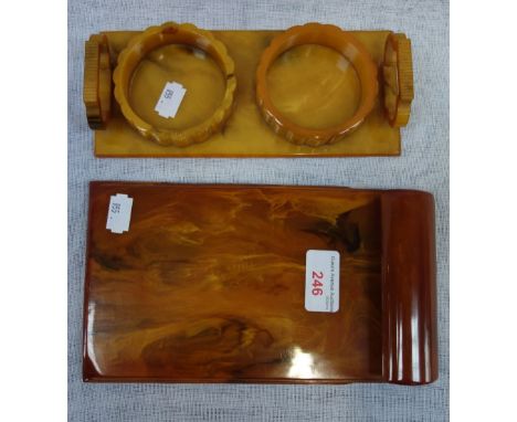 AN AMBER COLOURED EARLY PLASTIC "CARVACRAFT" NOTEPAD HOLDER and a similar bottle stand stamped "BP"
