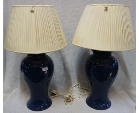 A PAIR OF LARGE BLUE CERAMIC TABLE LAMPS, of vase form with cream pleated silk shades, 71cm high overall