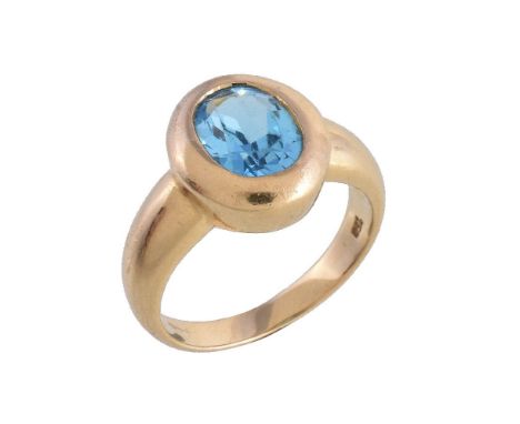 A blue topaz dress ring, the oval cut blue topaz within a polished gold coloured setting, the shank stamped 750 with Birmingh