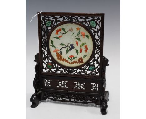 A Chinese hardstone table screen with flowers and foliage pattern, the circular plaque mounted in a reticulated wooden stand 