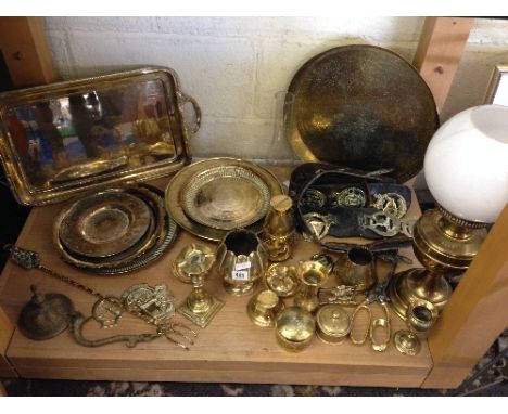 A shelf containing a large quantity of various brass items including Eastern brass and horse brasses.