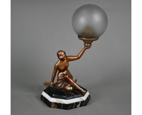 An Art Deco gold-patinated spelter figural lamp as a semi-nude female holding aloft a frosted glass globe shade, seated on oc