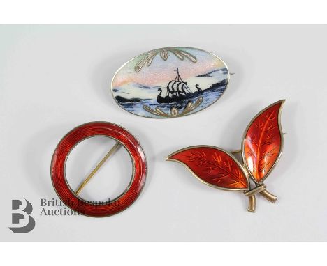 Three Norwegian silver and enamel brooches, including a red leaf brooch, circular scarf ring and an oval brooch depicting a l