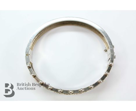 A silver bangle, heightened with gold, approx 60mm.