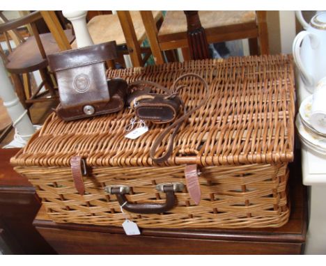 A vintage wicker picnic hamper and a leather-cased camera