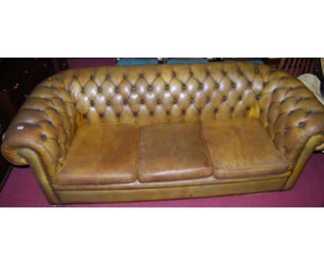 A greenish tan leather upholstered three seater button back Chesterfield, raised on squat bun forelegs, width 210cm